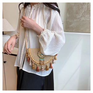 Détail du sac bandoulière tissé avec perles colorées, franges en métal et pompons