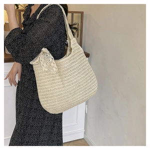Detail view of woven straw tote bag featuring delicate white lace bow and texture