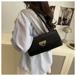 Detailed view of black woven texture shoulder bag featuring gold horseshoe metal buckle