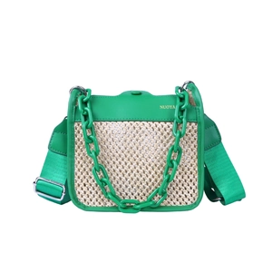 Green leather and raffia woven shoulder bag with chunky chain and wide strap on white background