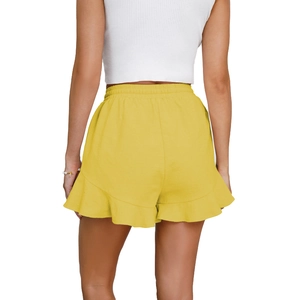 Detail of yellow high-waisted shorts with ruffled hem and elastic drawstring waistband