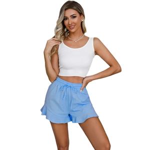 Detail of white ribbed tank top and light blue ruffle hem drawstring cotton linen shorts
