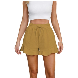 Detail of high waist linen shorts with drawstring and ruffled hem in ginger gold