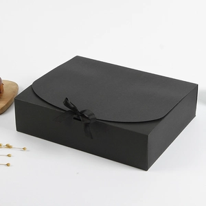 Detail einer eleganten schwarzen Geschenkbox mit Satinschleife und geschwungenem Deckel