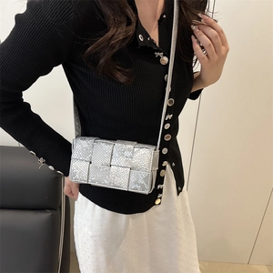 Silberne gewebte Umhängetasche mit metallischer Schuppenstruktur am Modell getragen