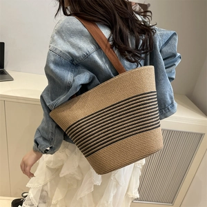 Large woven tote bag with dark camel stripes and chocolate fabric strap on a model