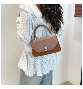 Detail of brown woven texture handbag with golden BB metal buckle and leather handle