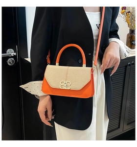 Detail of weaving texture and golden metal buckle on orange crossbody handbag