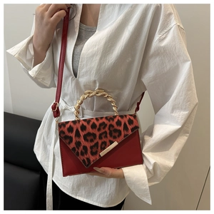 Dettaglio della borsa in pelle rossa con patta leopardata e tracolla a catena dorata spessa