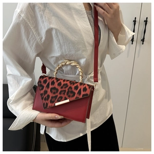 Dettaglio borsa in pelle rossa con patta leopardata e manico in metallo dorato