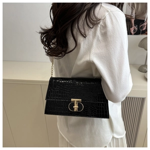 Detail of black crocodile texture shoulder bag with golden chain and T-shaped metal clasp