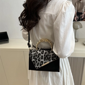 Borsa a tracolla leopardata chic con manico dorato indossata da modella in bianco