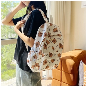 Detail view of large white backpack with cute Capybara patterns worn by model in soft light