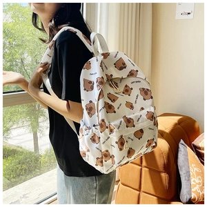 Detail of white Capybara backpack with cartoon print worn by model in cozy interior