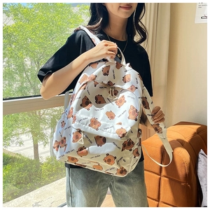 Detail of white canvas backpack featuring cute Capybara cartoon prints and durable zippers