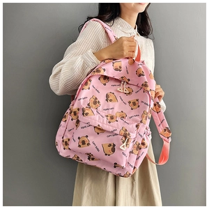 Detail of pink backpack featuring all-over cartoon capybara print worn by a model