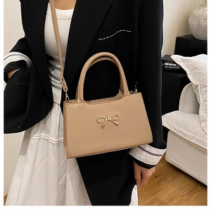 Vue détaillée du sac à bandoulière beige à nœud sur un mannequin pour la taille
