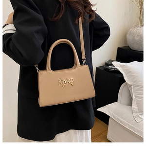 Détail d'un sac bandoulière beige abricot avec boucle en métal doré en forme de nœud