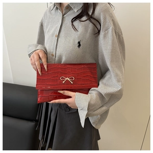 Detail of red crocodile texture envelope clutch bag with gold butterfly clasp decor