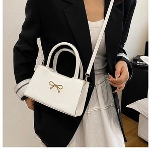 Détail du sac bandoulière en cuir PU blanc avec nœud doré élégant et poignée supérieure