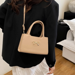 Sac bandoulière en cuir abricot chic avec nœud doré présenté dans un décor moderne chic