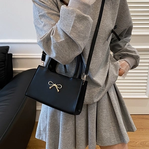 Sac bandoulière minimaliste en similicuir noir avec un nœud doré décoratif et élégant