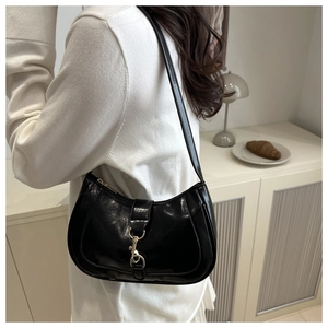 Détail d'un sac demi-lune en cuir noir brillant avec un fermoir crochet doré chic