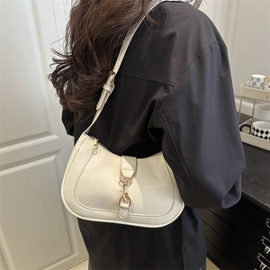Sac hobo blanc brillant avec détails dorés porté par un mannequin au style chic