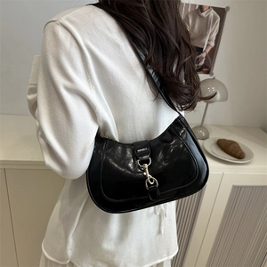 Élégant sac bandoulière croissant noir avec boucle dorée porté par un mannequin en studio