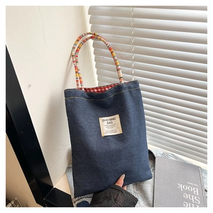 Dettaglio della borsa tote in denim con manici colorati intrecciati ed etichetta vintage
