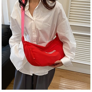 Close-up of red crescent crossbody bag with pink strap and white 'FASHION' text print
