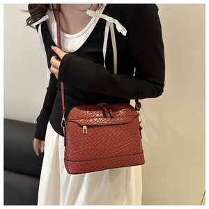 Gros plan du sac coquillage tressé rouge-brun avec fermeture éclair dorée élégante