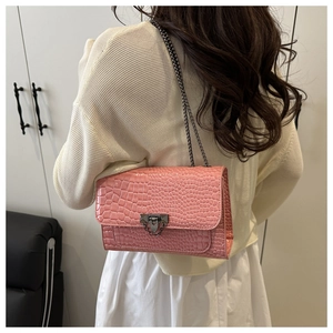 Pink croc-embossed shoulder bag with dark metal chain and clasp shown on a model