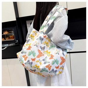 Grand sac cabas blanc avec motifs papillons colorés porté dans un décor moderne