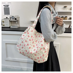 Detailed texture of floral canvas tote bag with pink roses and red ribbon pattern