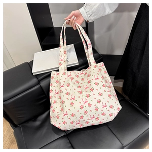 Détail du cabas en toile crème avec motifs floraux roses et imprimé nœud élégant
