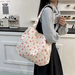 Floral canvas tote bag with pink bow patterns for women shown in a modern cafe setting