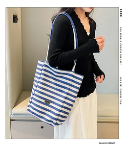 Side view of blue and white striped canvas tote bag with metal logo on a model
