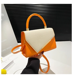 Detail of orange and beige woven leather handbag with gold metal trim and rigid handle