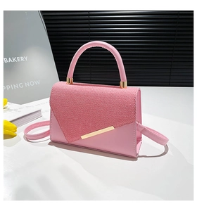 Detail of pink leather handbag with textured flap and elegant gold metal trim