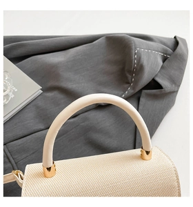 Detailed view of woven texture and cream leather handle with gold metal accents