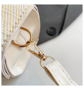 Macro shot of detachable gold lobster clasp and beige leather strap on woven handbag