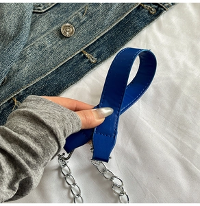 Détail de la bandoulière en cuir bleu foncé avec chaîne en argent et coutures fines
