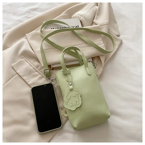 Detail of mint green mini bag with fashion lettering and cute dog charm on white fabric