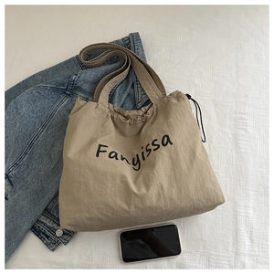 Detail view of khaki nylon tote bag with drawstring closure and Fanyissa letter print