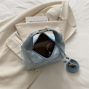 Detail of light blue floral embossed handbag interior showing capacity on beige blazer