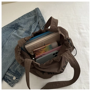 Detail view of large brown nylon drawstring tote bag with interior storage items