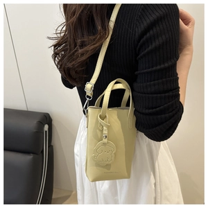 Detail of yellow PU leather crossbody phone bag with dog charm and fashion text