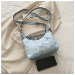 Close-up of light blue shoulder bag with white floral lace and 3D butterfly details
