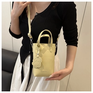 Detailed look at yellow mini tote bag with puppy charm and slim crossbody strap